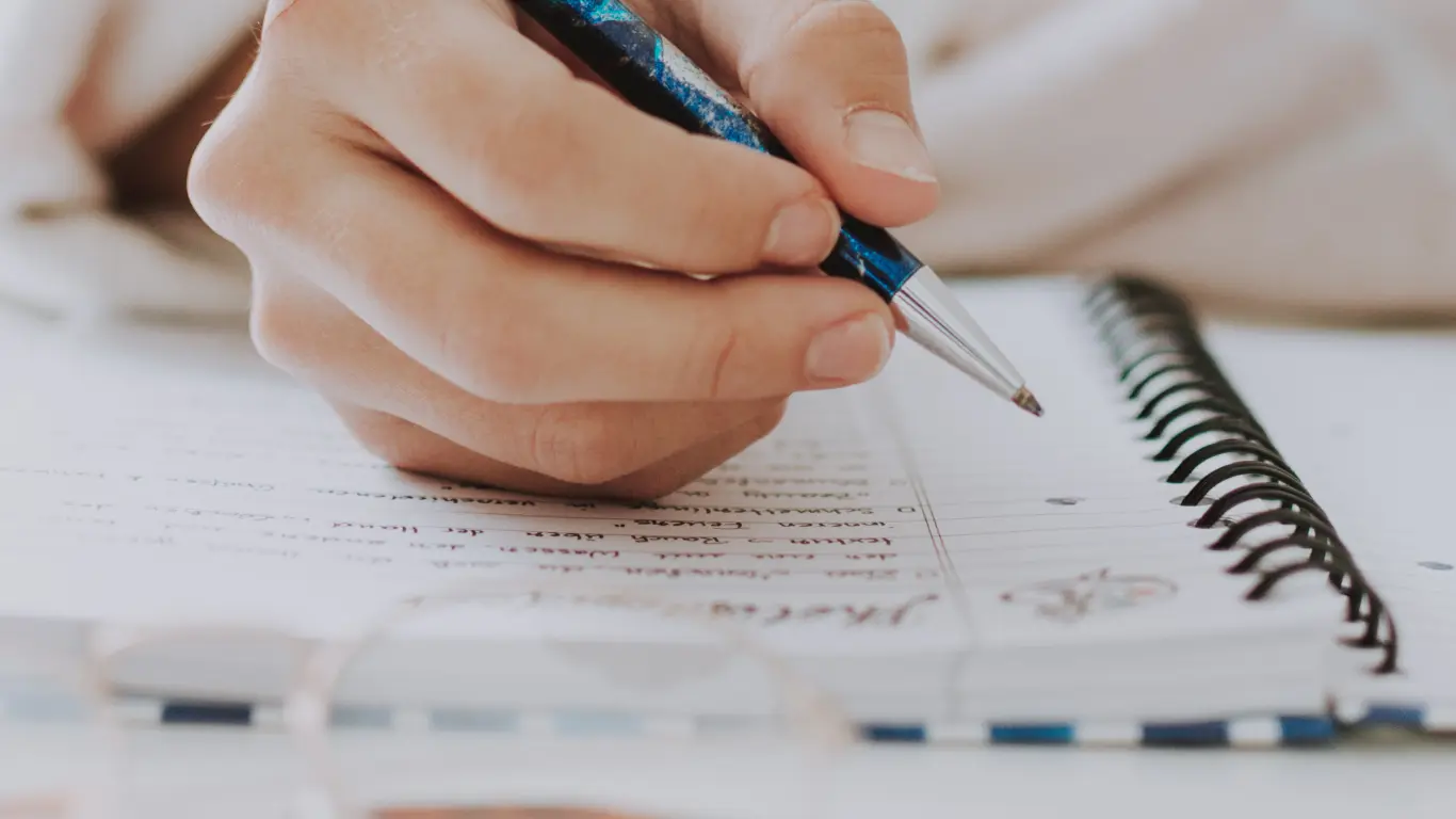 ACBC image of a person's hand holding a pen and writing down a strategy plan