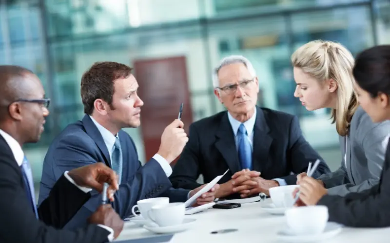 Action coach image of a group of business men and women talking and discussing businesses