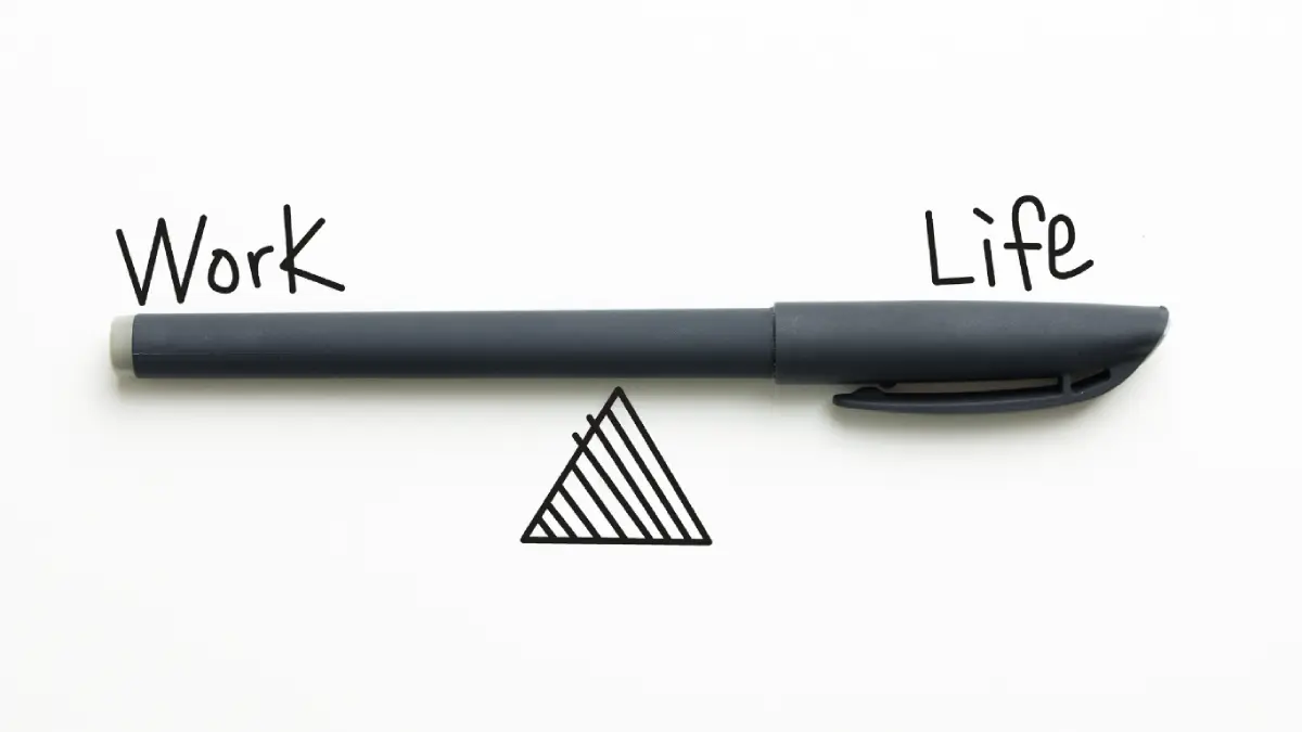 Action coach image of a pen balancing on a drawing of a triangle, with the words work and life on each side